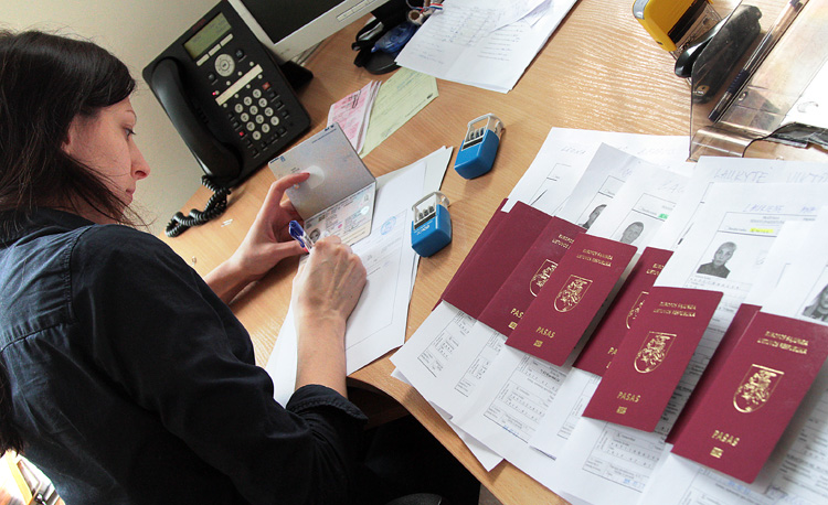 Kobieta pracująca przy stosie litewskich paszportów