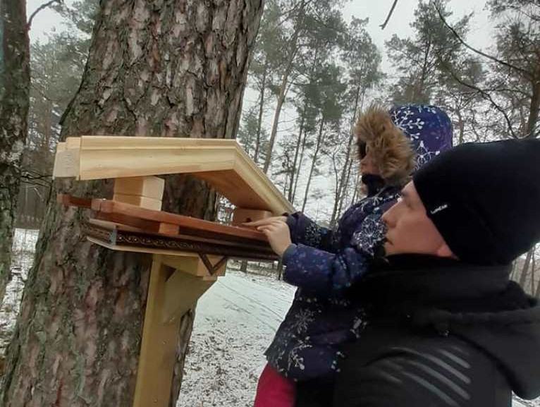 Andrej Smirnow z Mariampola zawiesza własnoręcznie wykonany drewniany karmnik dla ptakówm