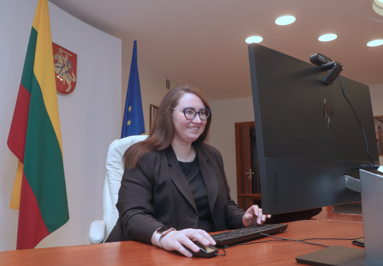 Ewelina Dobrowolska siedzi w białym fotelu, uśmiecha się do komputera trzymając niepewnie myszkę komputerową i naciskając przyciski na klawiaturze.