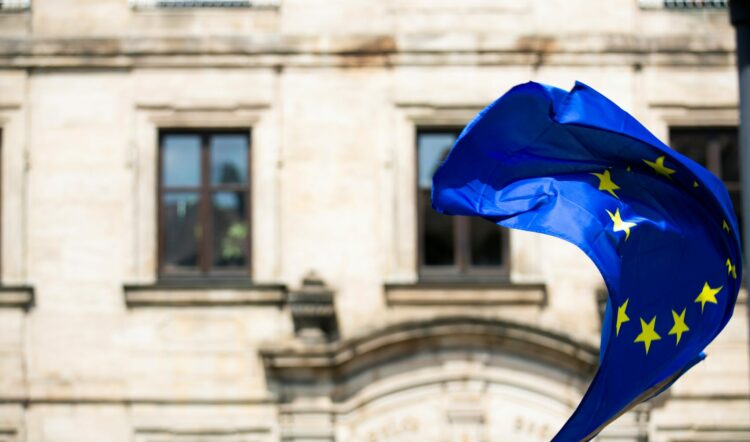 Flaga Unii Europejskiej powiewająca na tle starej kamienicy