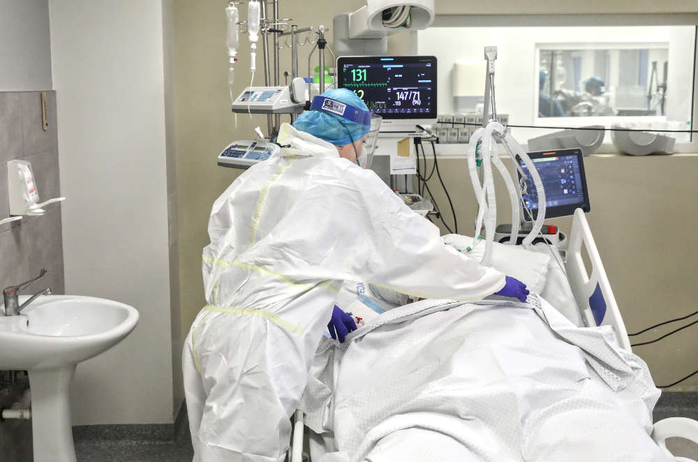 Medyk opiekuje się chorym pacjentem w szpitalu na Litwie.