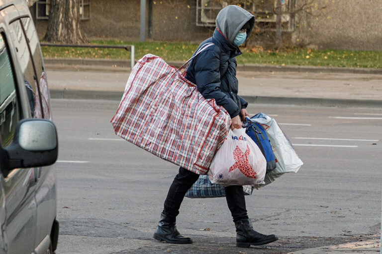Kobieta obładowana torbami na ulicy.