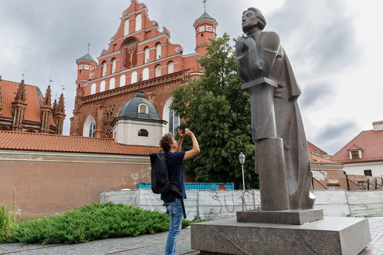 Chłopiec robi zdjecie pomnika Adama Mickiewicza.