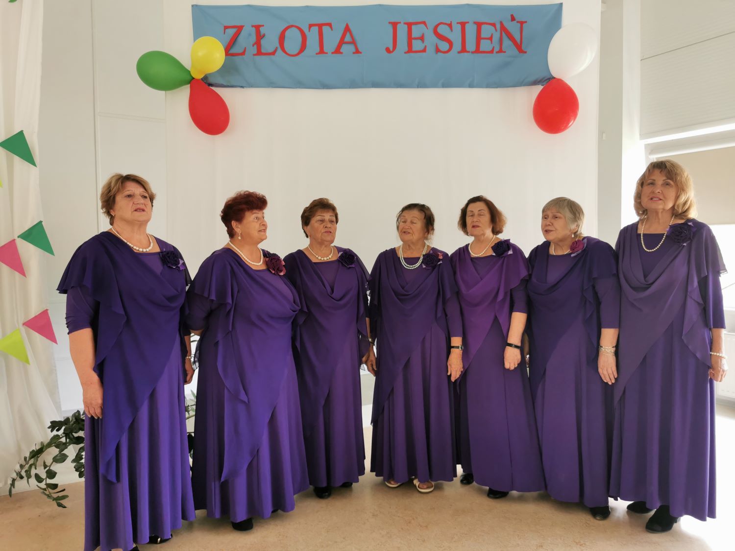 Śpiewające kobiety w fioletowych strojach.