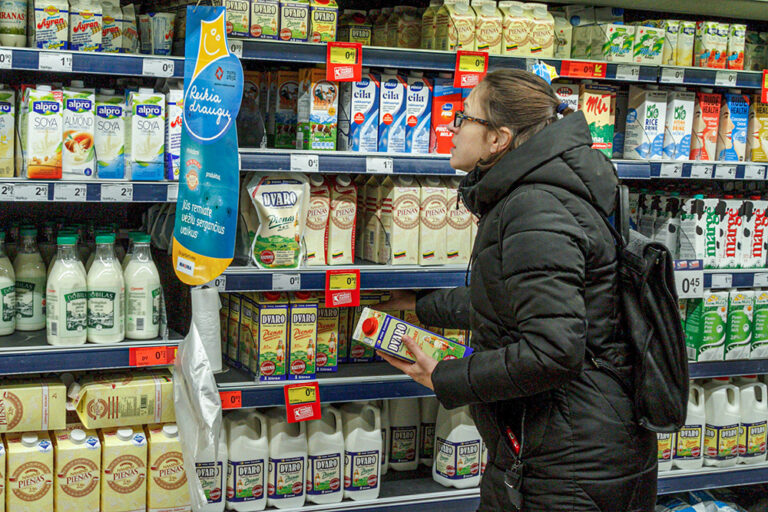 Kobieta w sklepie wybiera produkty mleczne.
