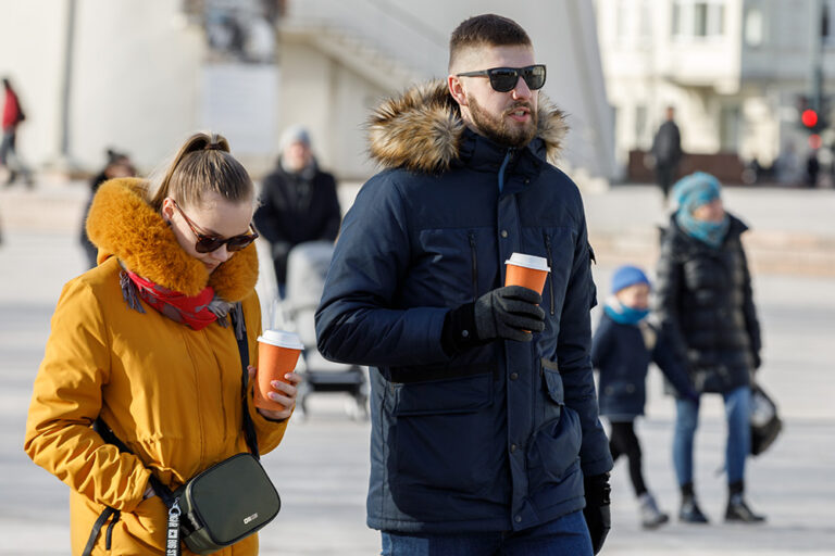 Kobieta z mężczyzną pija kawę na spacerze.