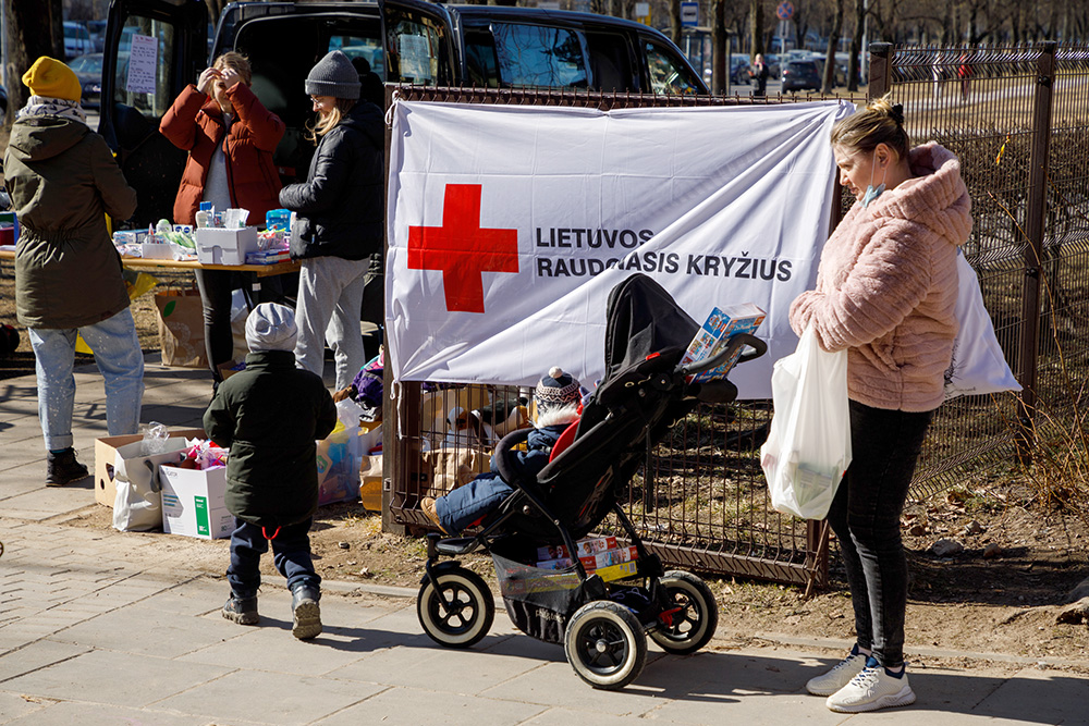 Kobieta z dziećmi z Ukrainy obok Litewskiego Czerwonego Krzyża.