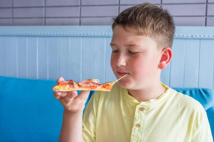Chłopczyk jedzący pizzę.