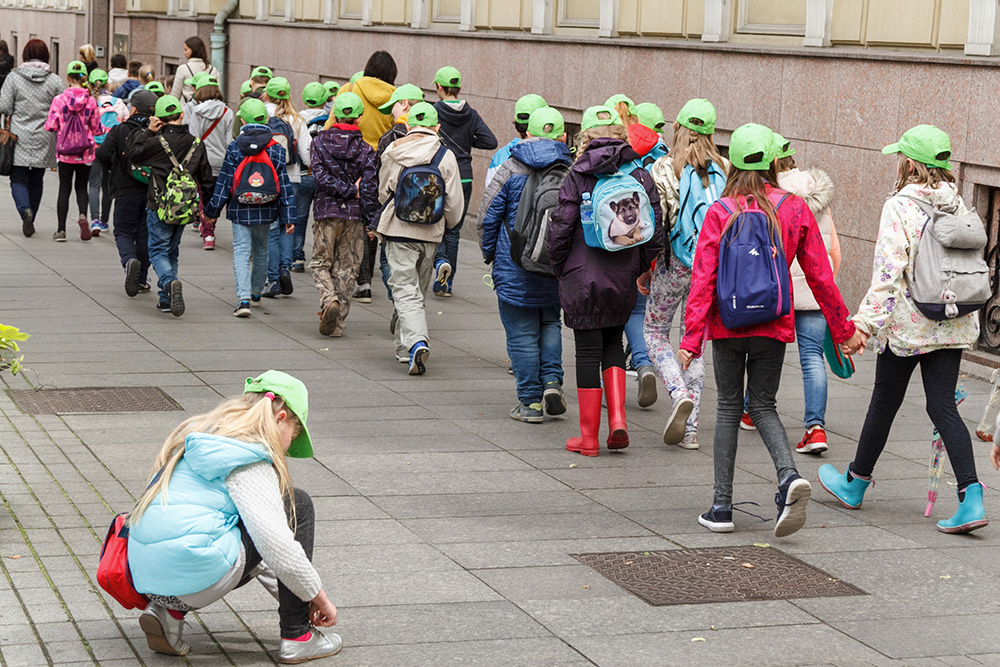Dzieci w parach maszerują po ulicy.
