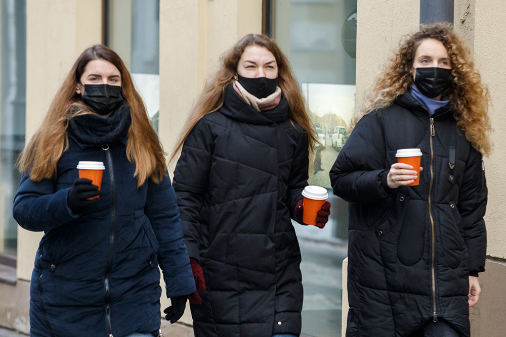 Trzy kobietki w maskach z kubeczkami kawy.