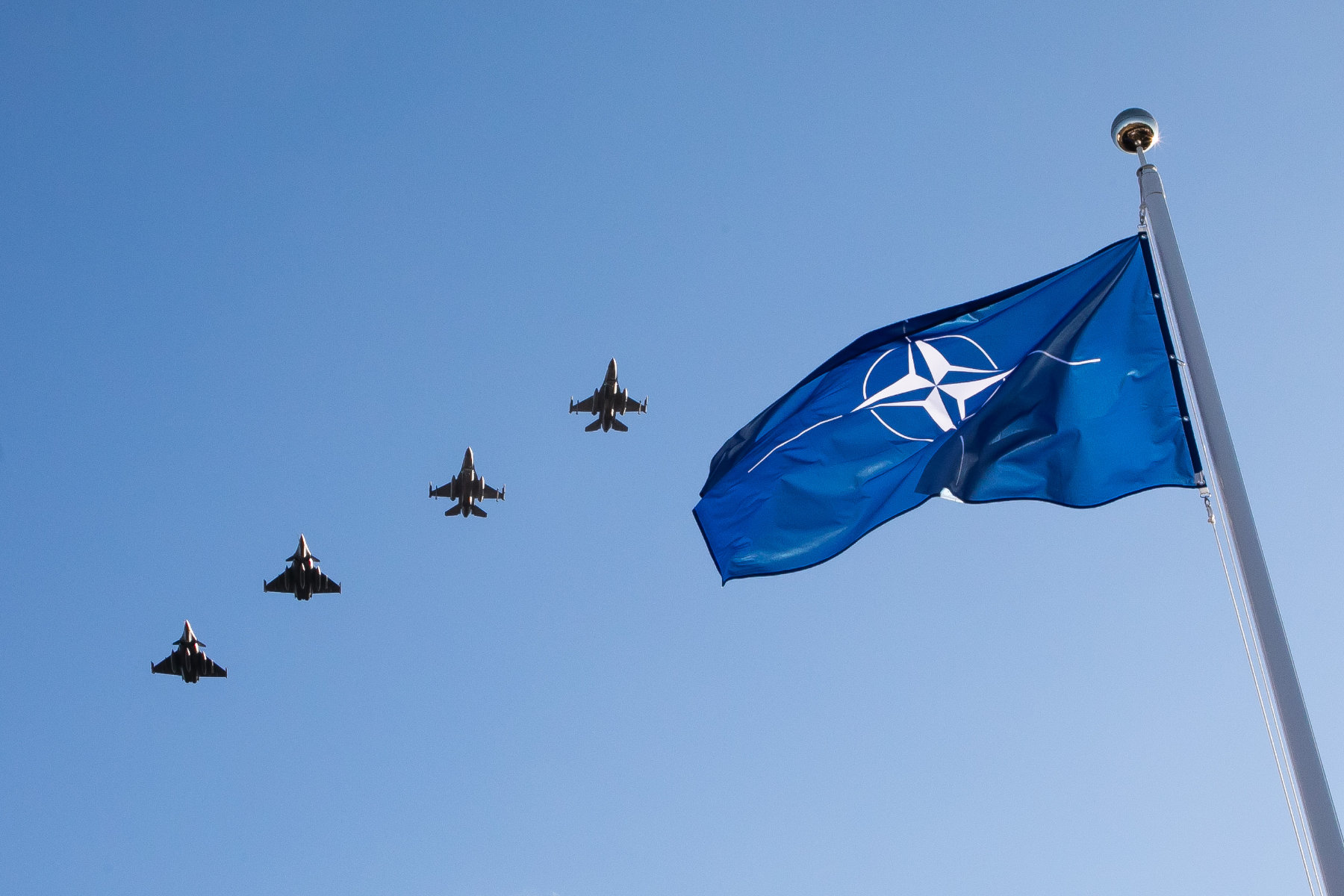 Flaga NATO, w tle samoloty w niebie.