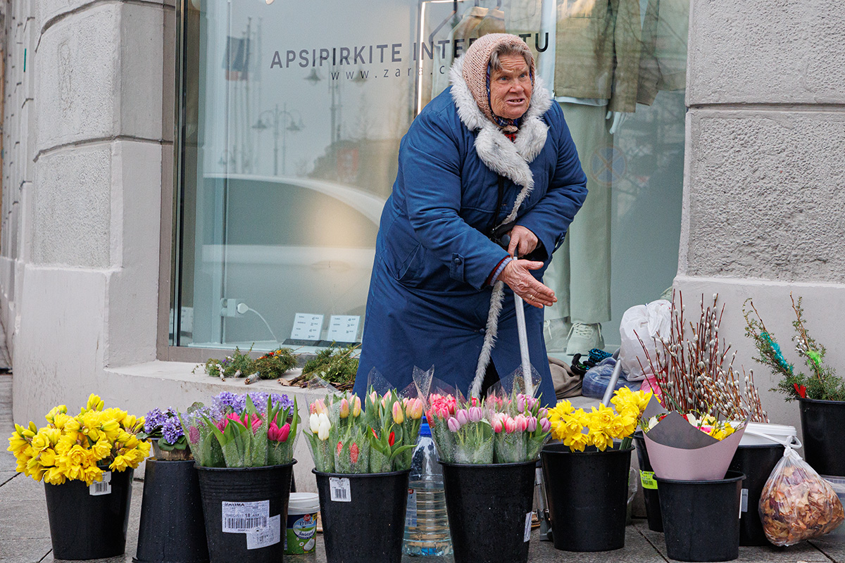 Emerytka sprzedaje kwiaty na ulicy.