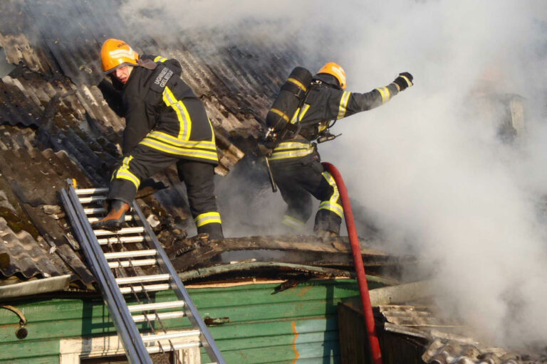 Strażacy na dachu gaszą pożar.
