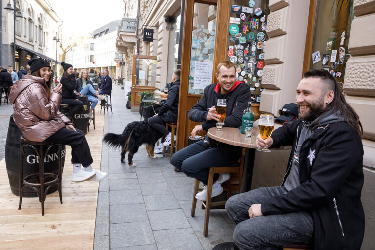 Mężczyźni pijące piwo w kawiarni na ulicy.