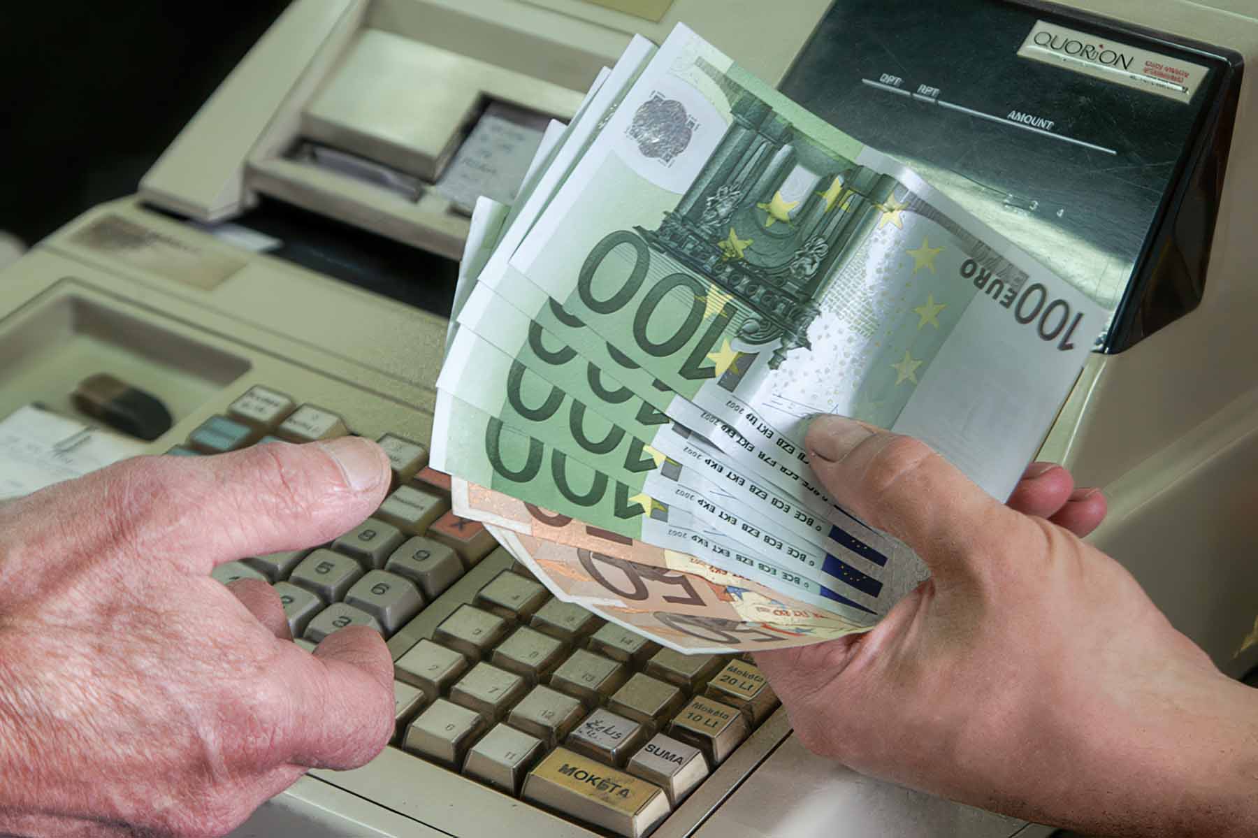 Człowiek trzyma euro przy kasie.