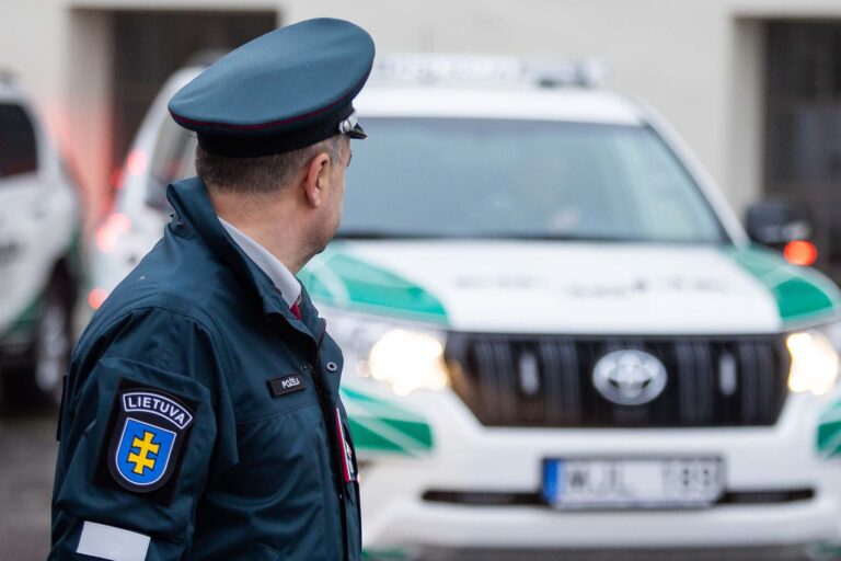 Policjant obok samochodu policyjnego.
