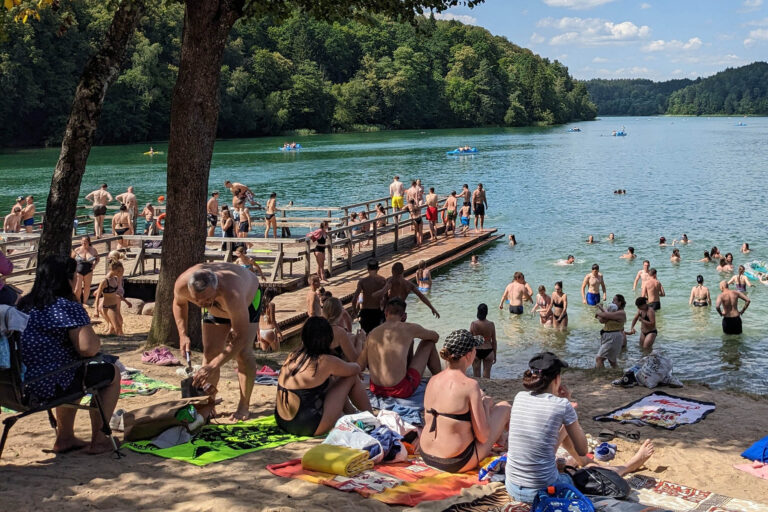 Ludzie opalają się obok jeziora.