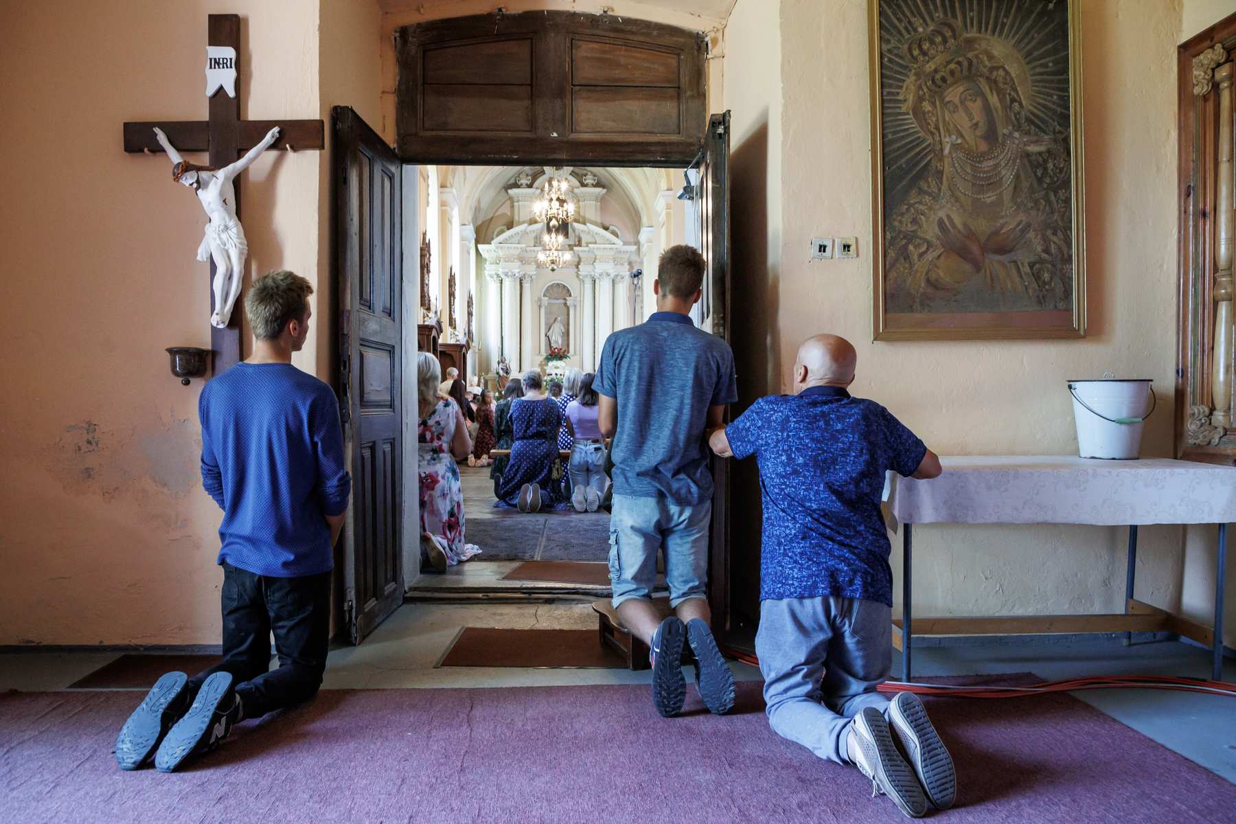 Ludzie na kolanach w kościele.