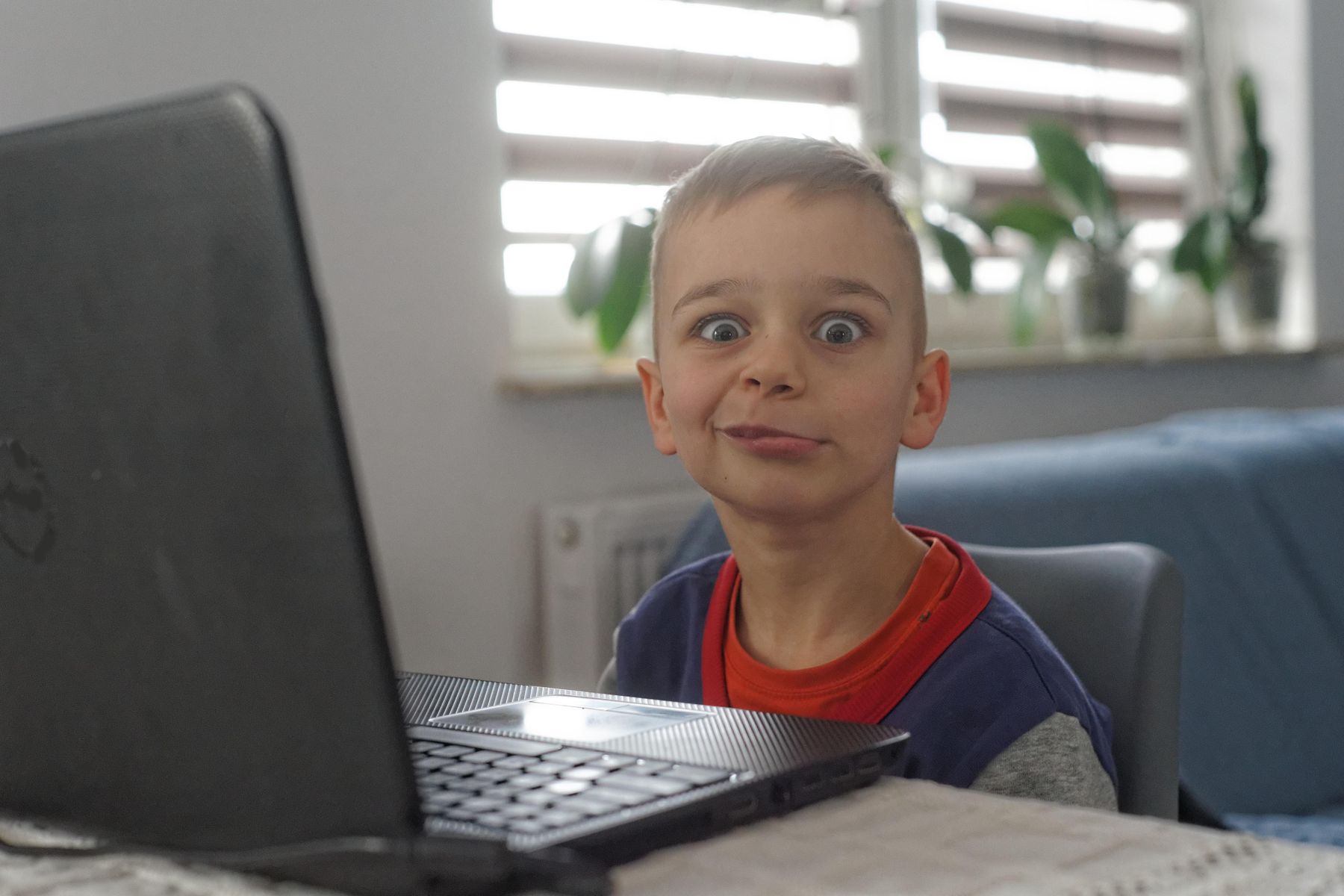 Dziecko wykrzywia się przed laptopem.
