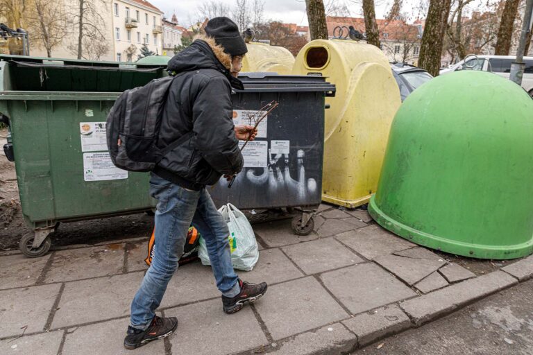 Bezdomny obok śmietników.