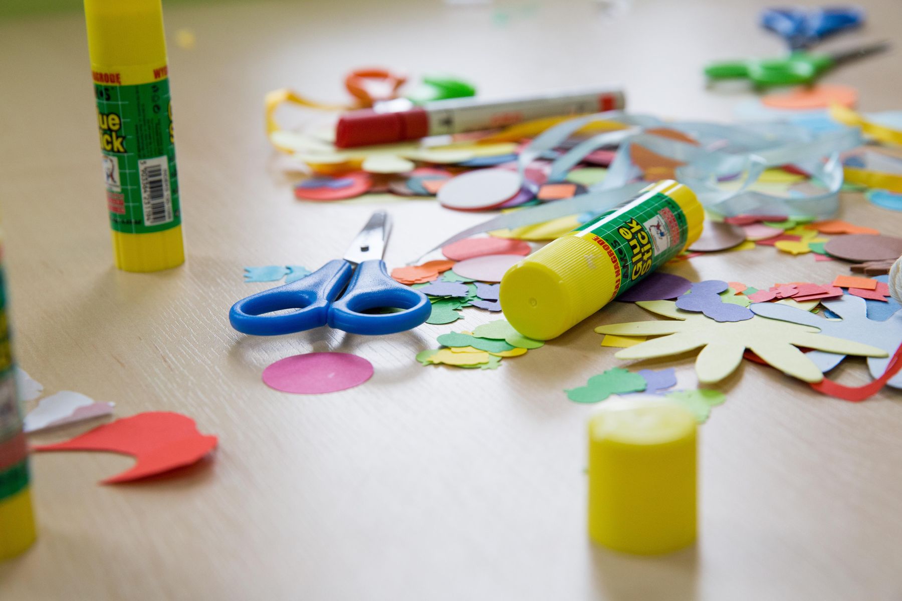 Nożyce, klej, papier na stole.