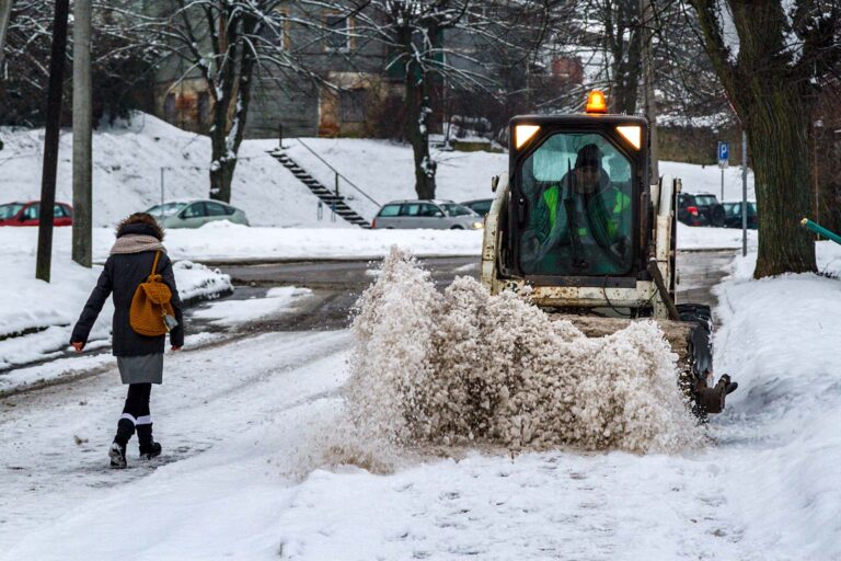Traktorek odśnieża ulicę.