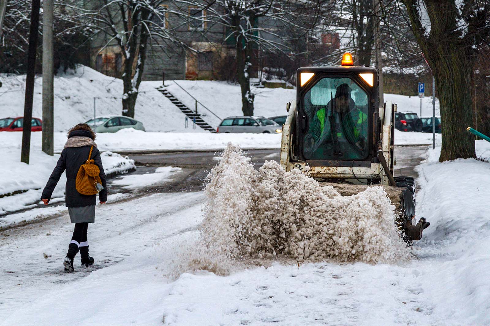 Traktorek odśnieża ulicę.