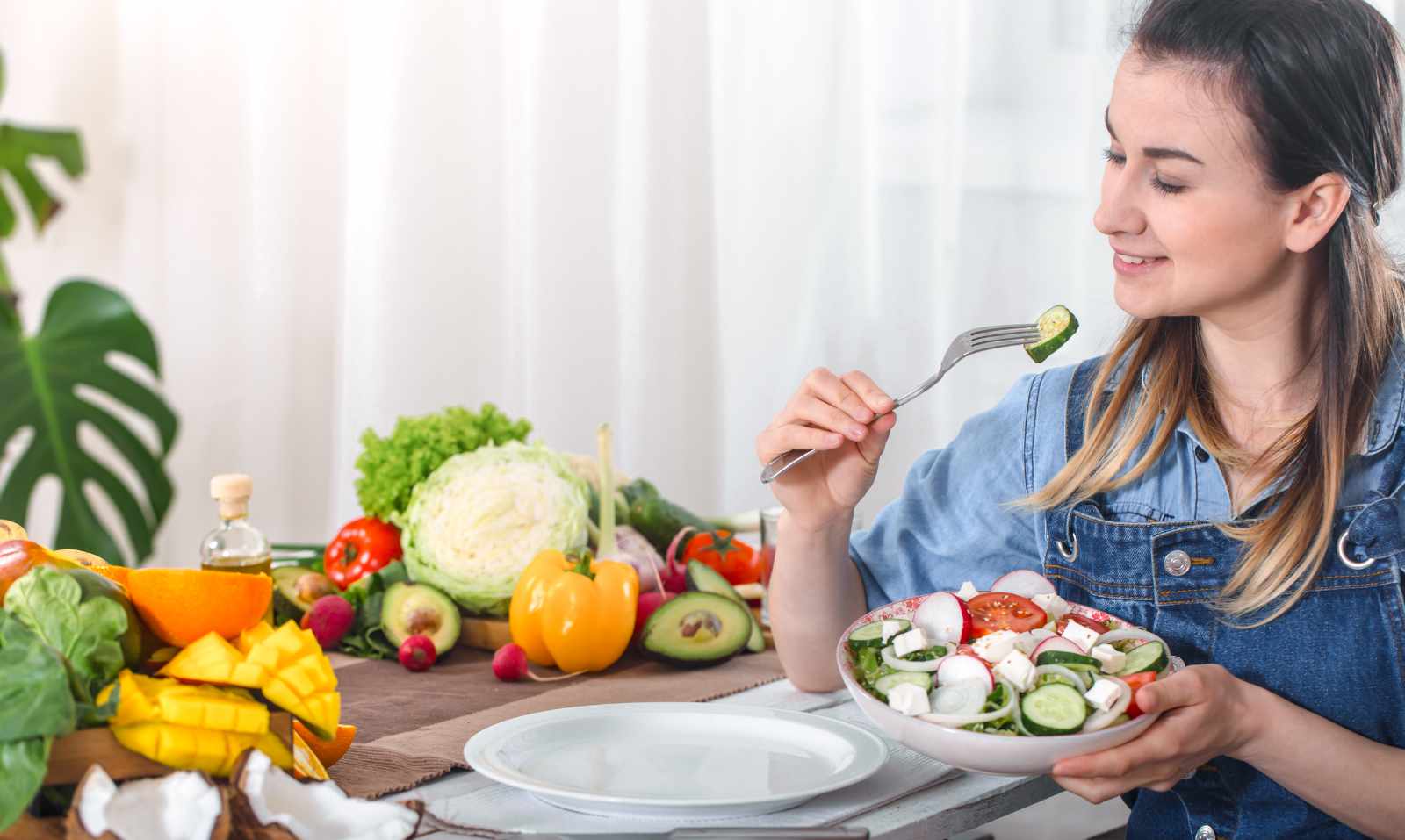 Young and happy woman eating salad at the table
