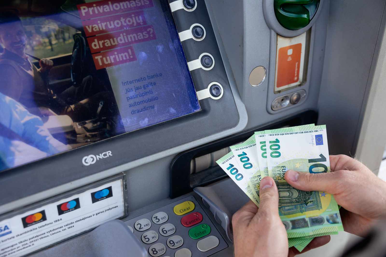 Banknoty po 100 euro obok bankomatu.