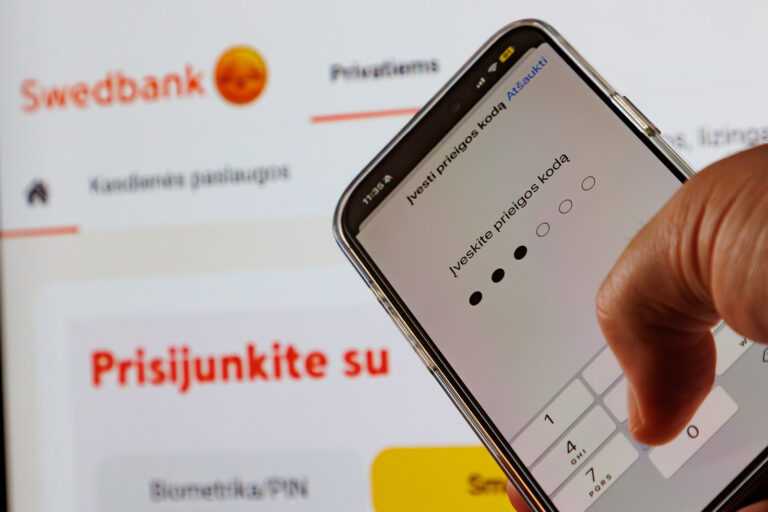 Telefon komórkowy na tle plakatu Swedbank.