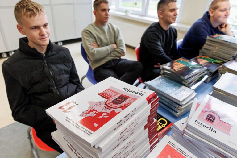 Uczniowie za ławkami obładowanym podręcznikami.