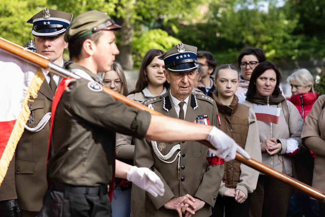 Harcerze niosą sztandar AK, obok stoi Stanisław Poźniak.