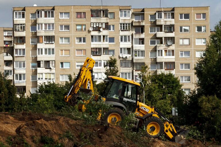 Blok wielomieszkaniowy. W tle traktor.