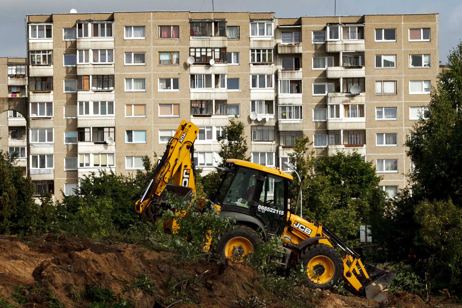 Blok wielomieszkaniowy. W tle traktor.