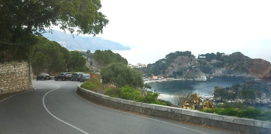 SPOL-Taormina-2026-09-01-1a-PORTAL Taormina leży w prowincji Mesyna, w północnej części wschodniego wybrzeża Sycylii, w połowie drogi między Mesyną a Katanią. Miasto rozciąga się od poziomu morza i urokliwych zatok aż po górskie szczyty.