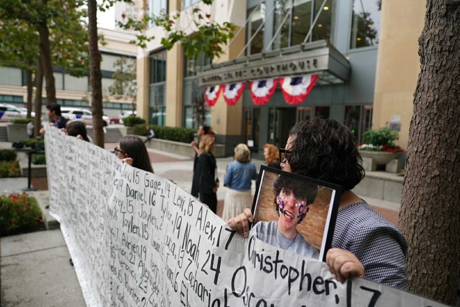 Rodzice protestujący przeciwko korporacji w USA trzymają transparenty z wizerunkami i imionami swoich dzieci, których już nie ma.