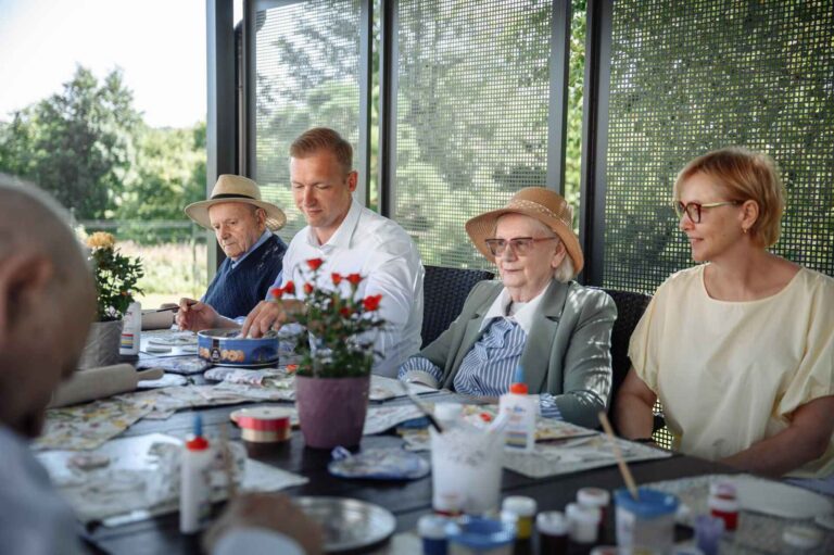 Seniorzy na warsztatach za stołem.